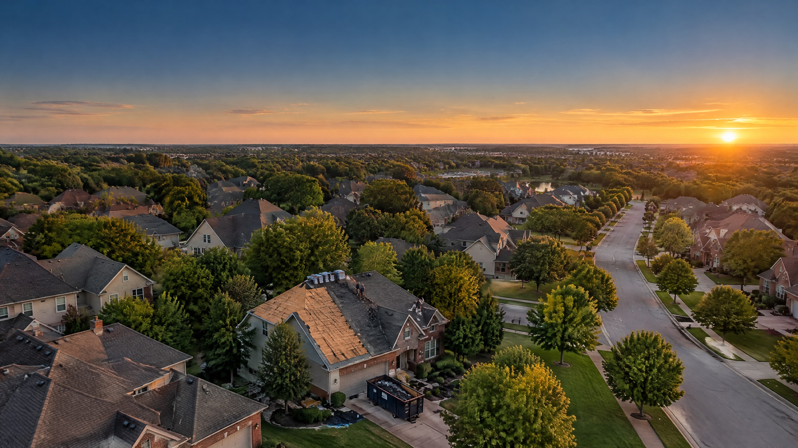 Aerial view of a suburban neighborhood with a roofing crew re-shingling a home
